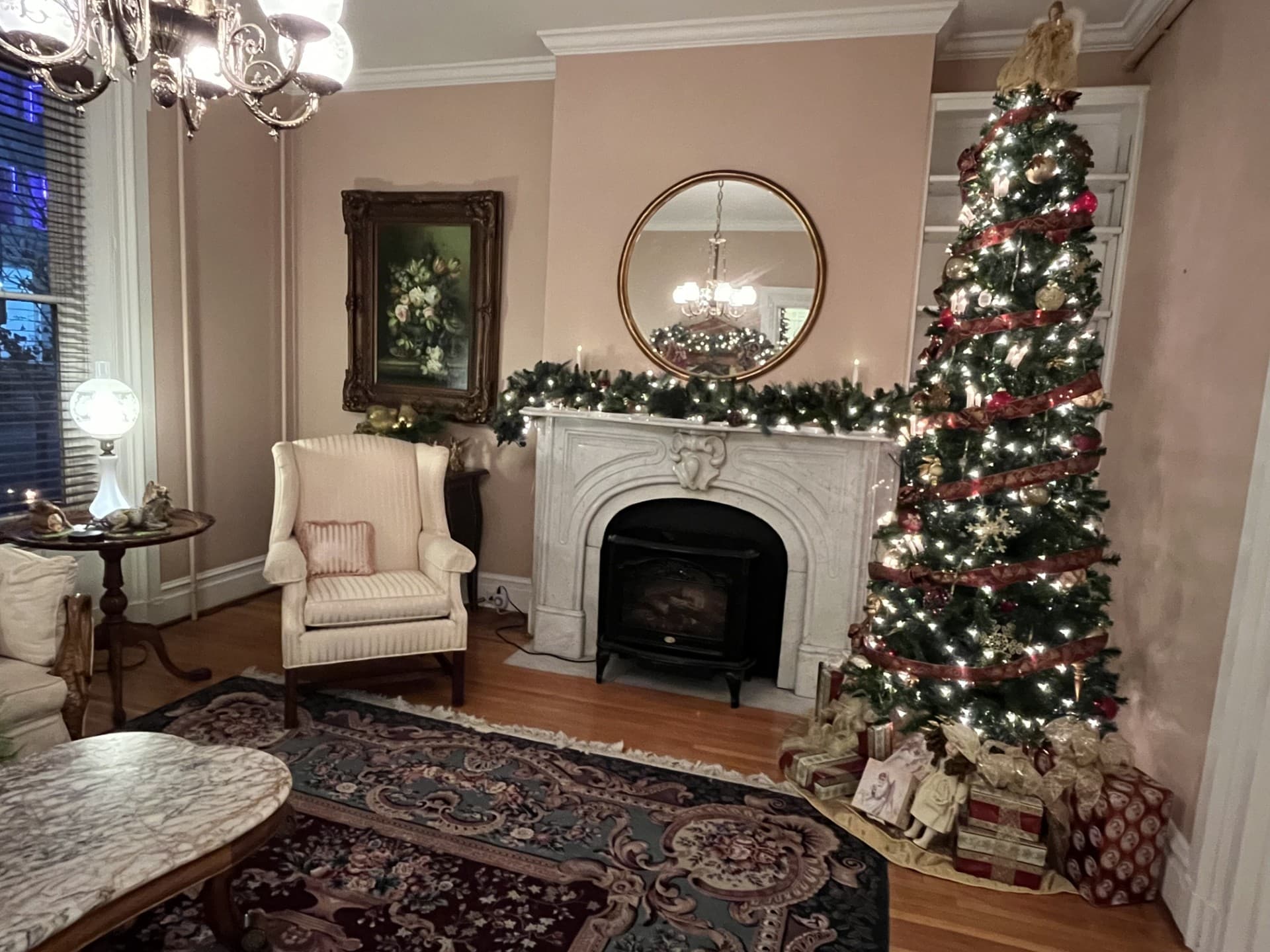 A cozy living room decorated for the holidays with a Christmas tree, gifts, and warm lighting.
