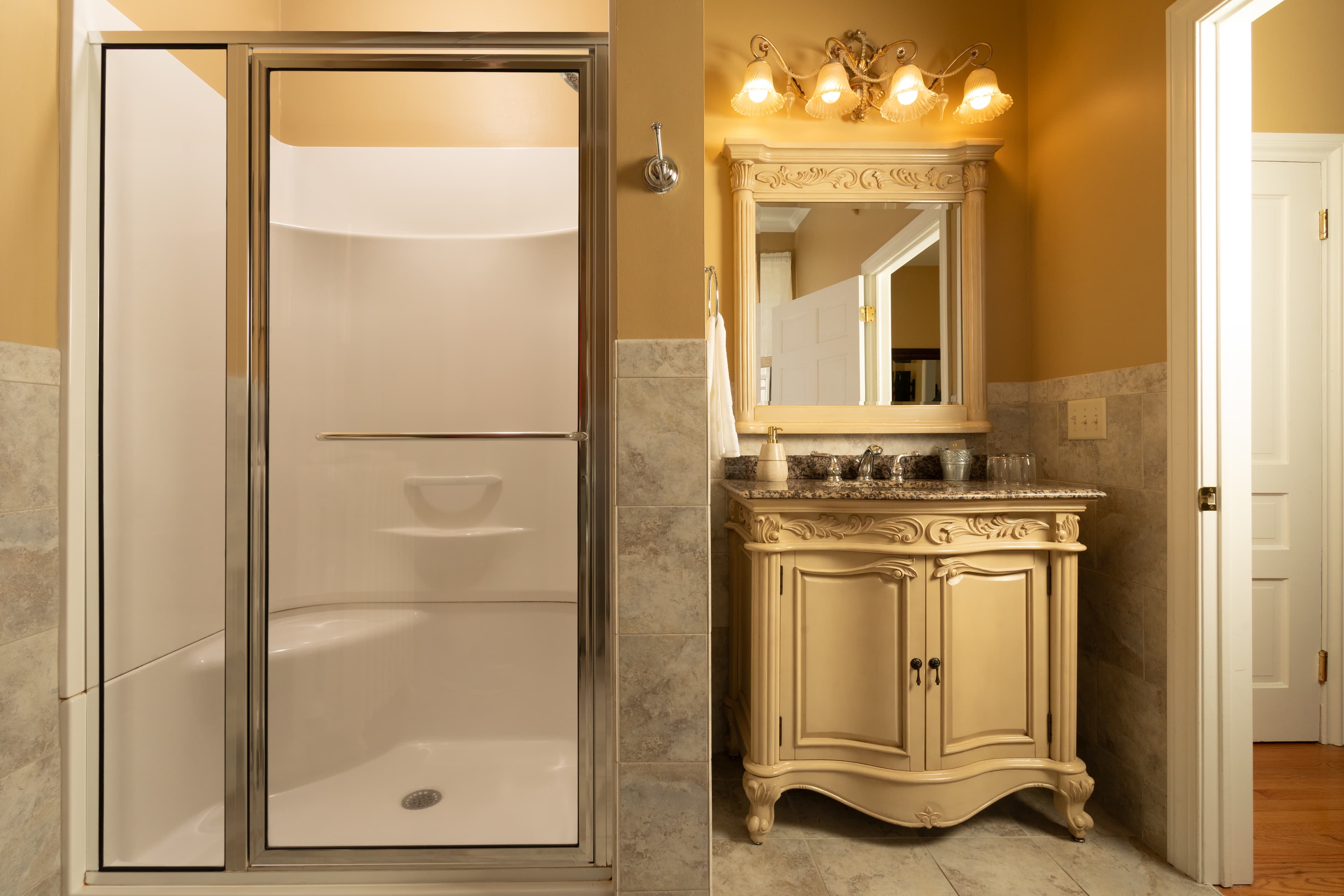 A modern bathroom featuring a glass shower and a vintage-style vanity with a mirror and decorative lighting.