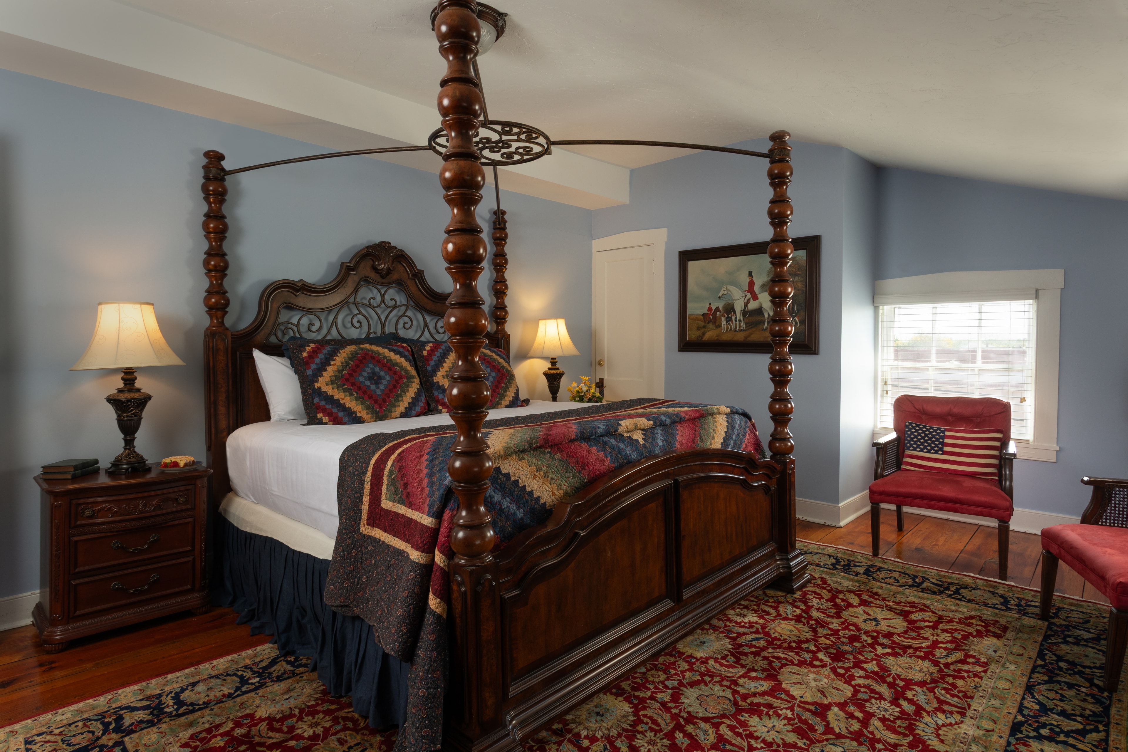 A cozy bedroom featuring a four-poster bed, decorative quilt, and warm lighting.