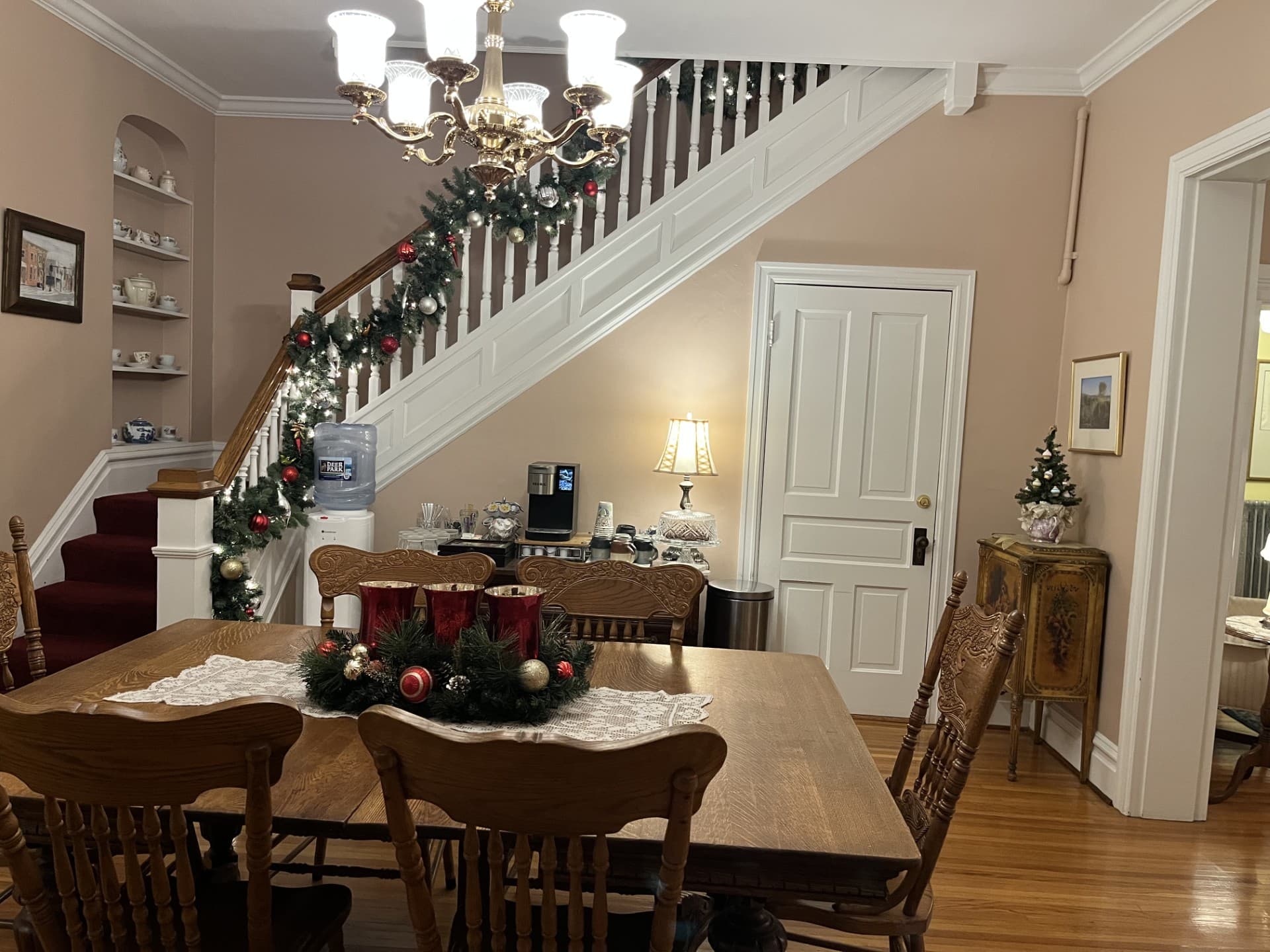 Cozy dining area featuring a wooden table, festive decorations, and a staircase adorned with garlands and ornaments.
