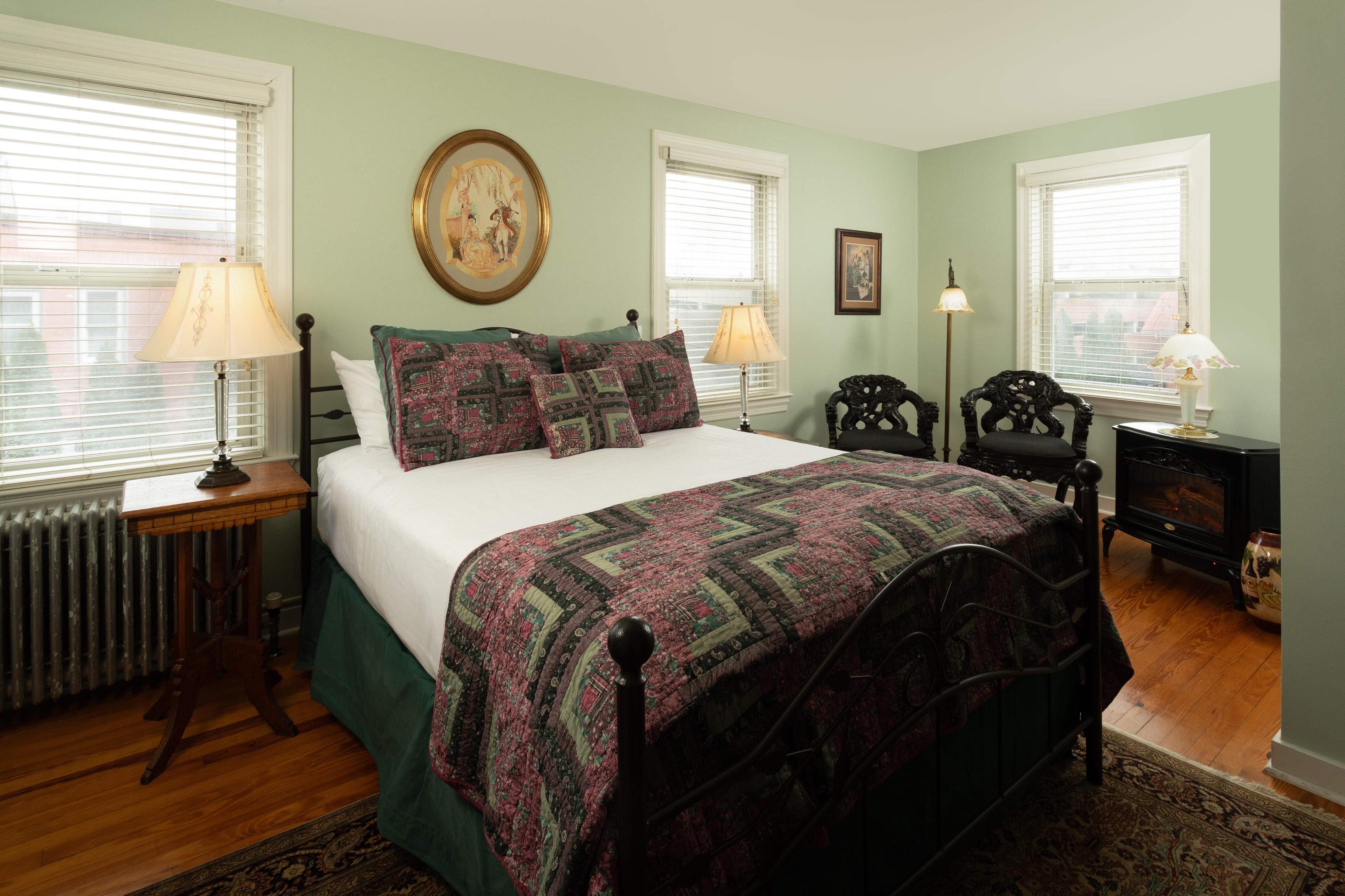 A cozy bedroom featuring a bed with a patterned quilt, two lamps on bedside tables, and decorative wall art.