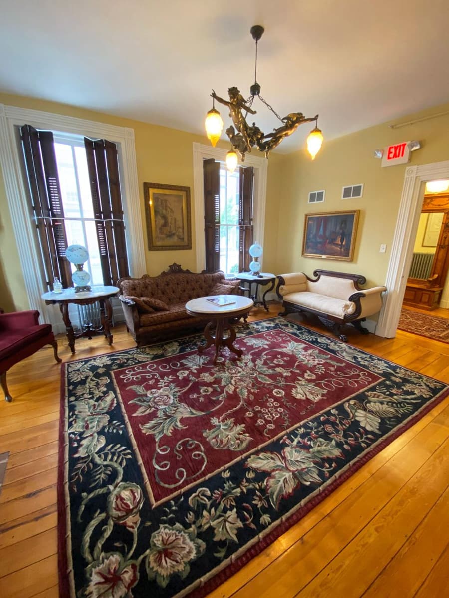 A cozy living room featuring elegant furniture, a floral rug, and decorative lighting.
