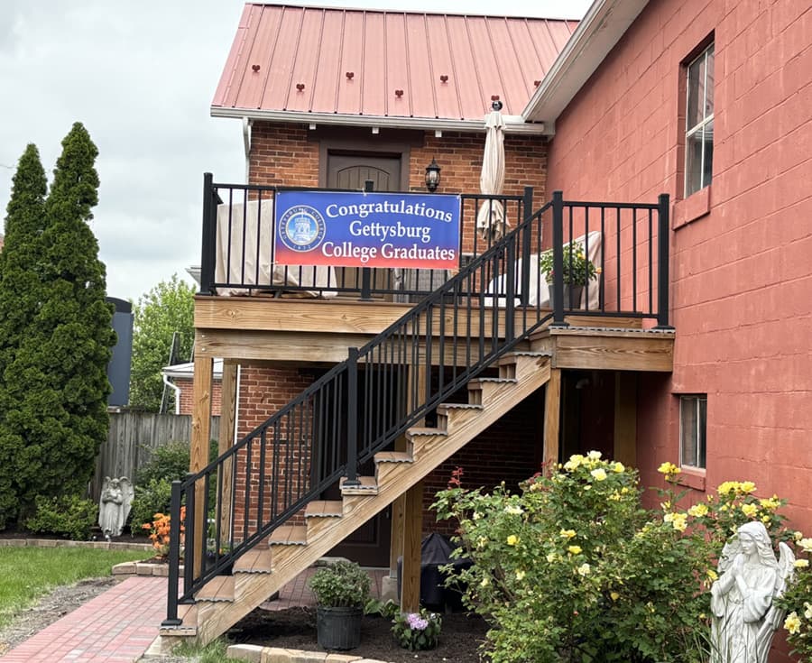 A sign on a staircase reads "Congratulations Gettysburg College Graduates" outside a brick building.