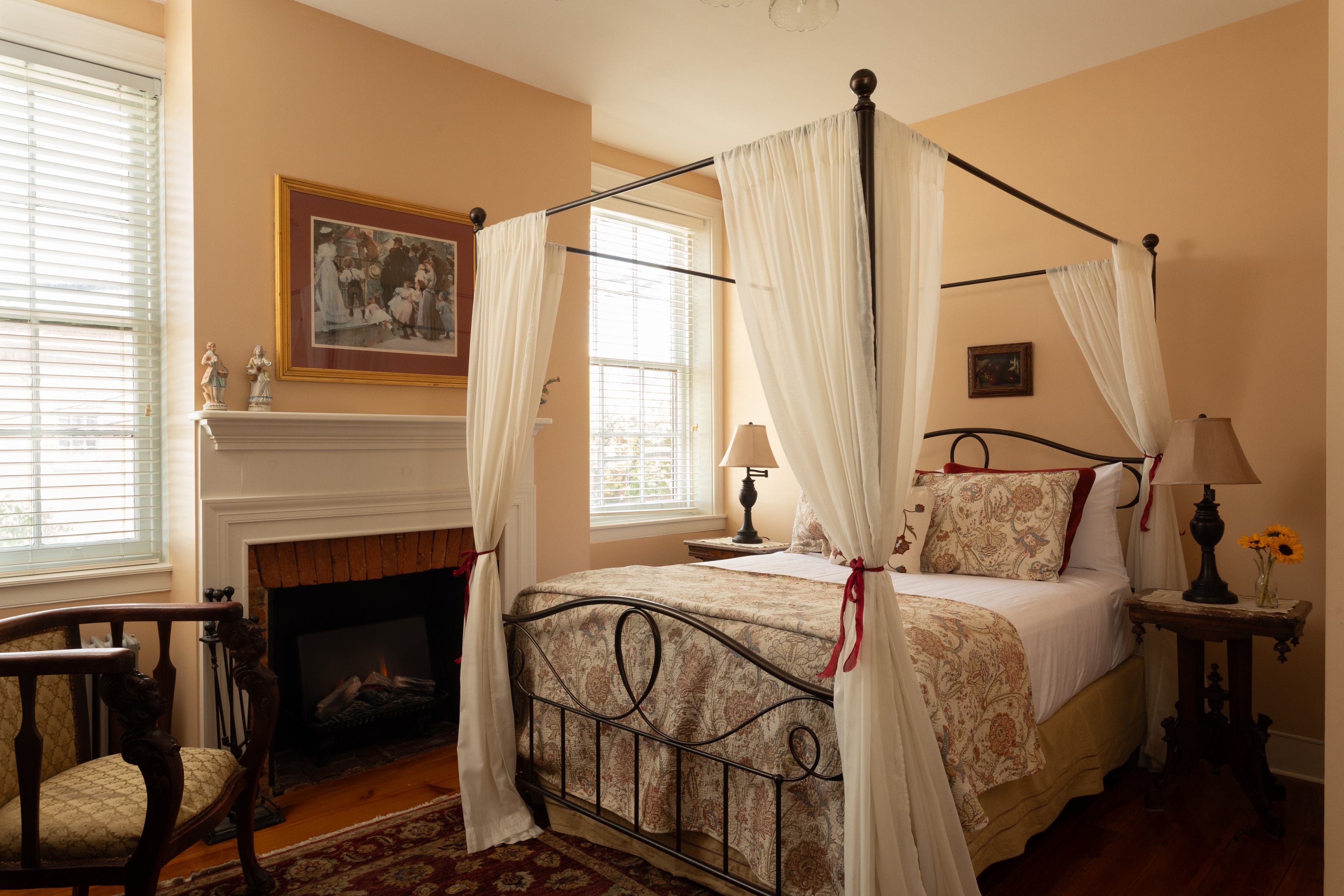 Cozy bedroom featuring a four-poster bed, fireplace, and warm decor.