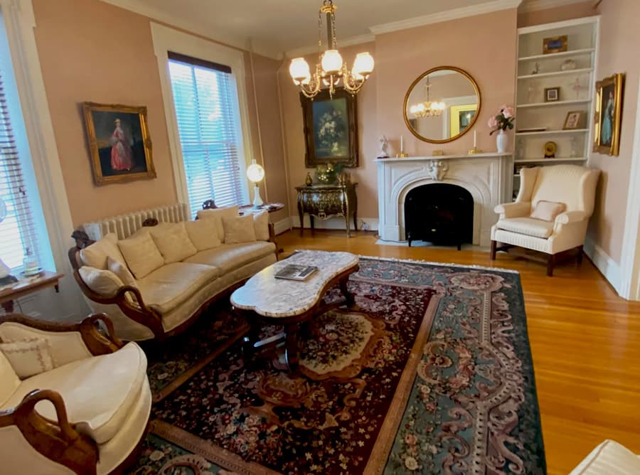 A cozy living room featuring a vintage sofa, ornate coffee table, and elegant decor on a patterned rug.