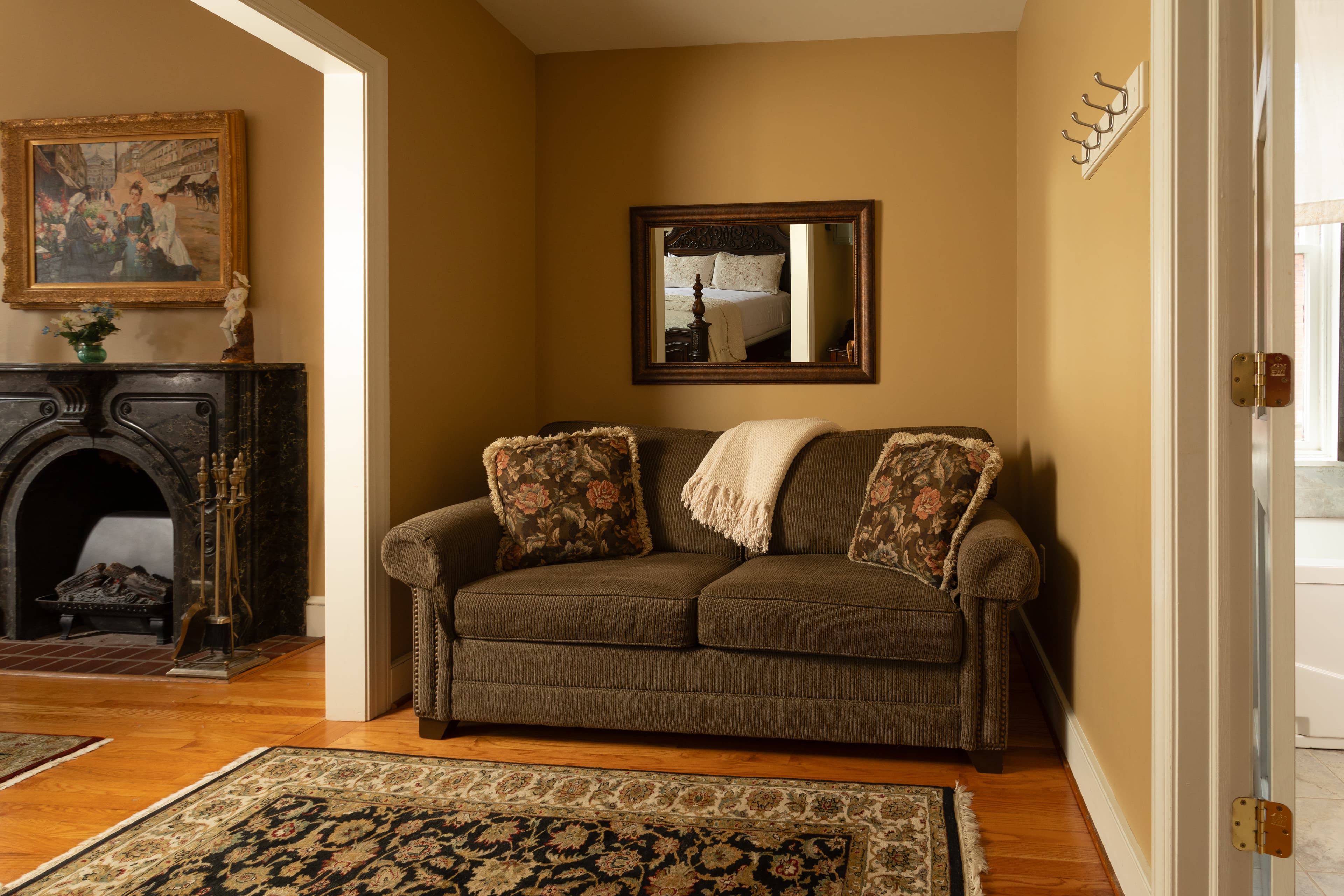 A cozy living area featuring a sofa with floral cushions, a decorative fireplace, and a mirror on the wall.