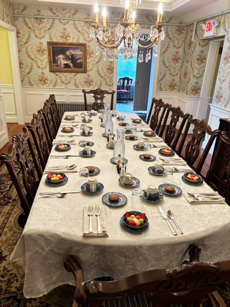 A beautifully set dining table with intricate blue dishes, silverware, and a chandelier overhead.