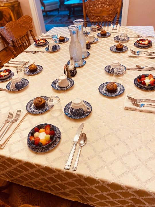 A well-set dining table with dessert plates, cups, and fruit bowls arranged neatly.