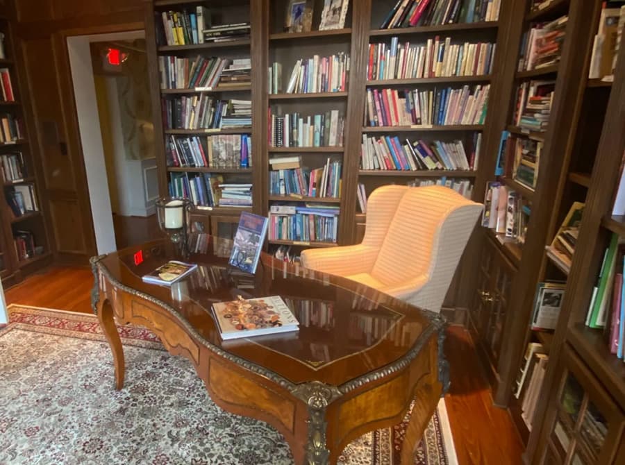 A cozy study with bookshelves, a wooden table, and two comfortable chairs.
