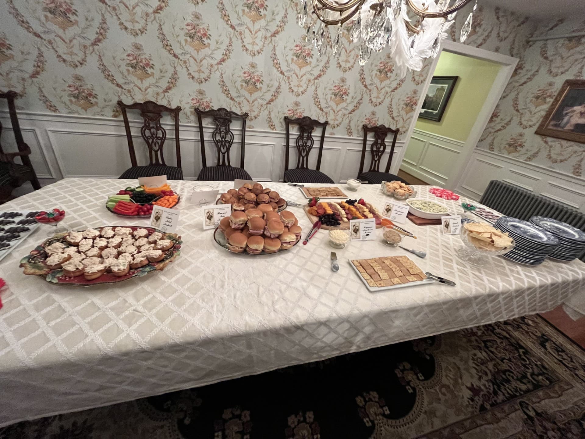 A banquet table is laden with a variety of appetizers, desserts, and fruits in an elegant dining room.