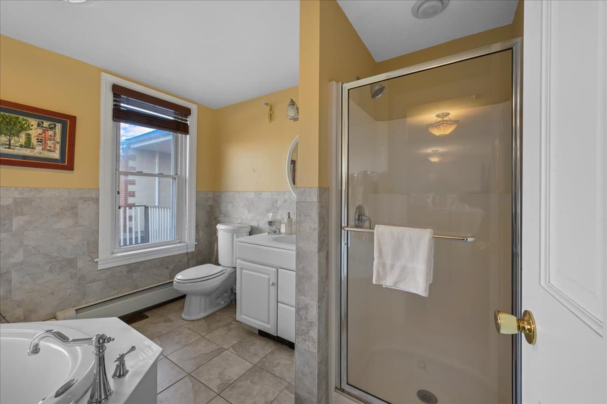 Bright bathroom featuring a shower, bathtub, and modern fixtures against yellow walls.