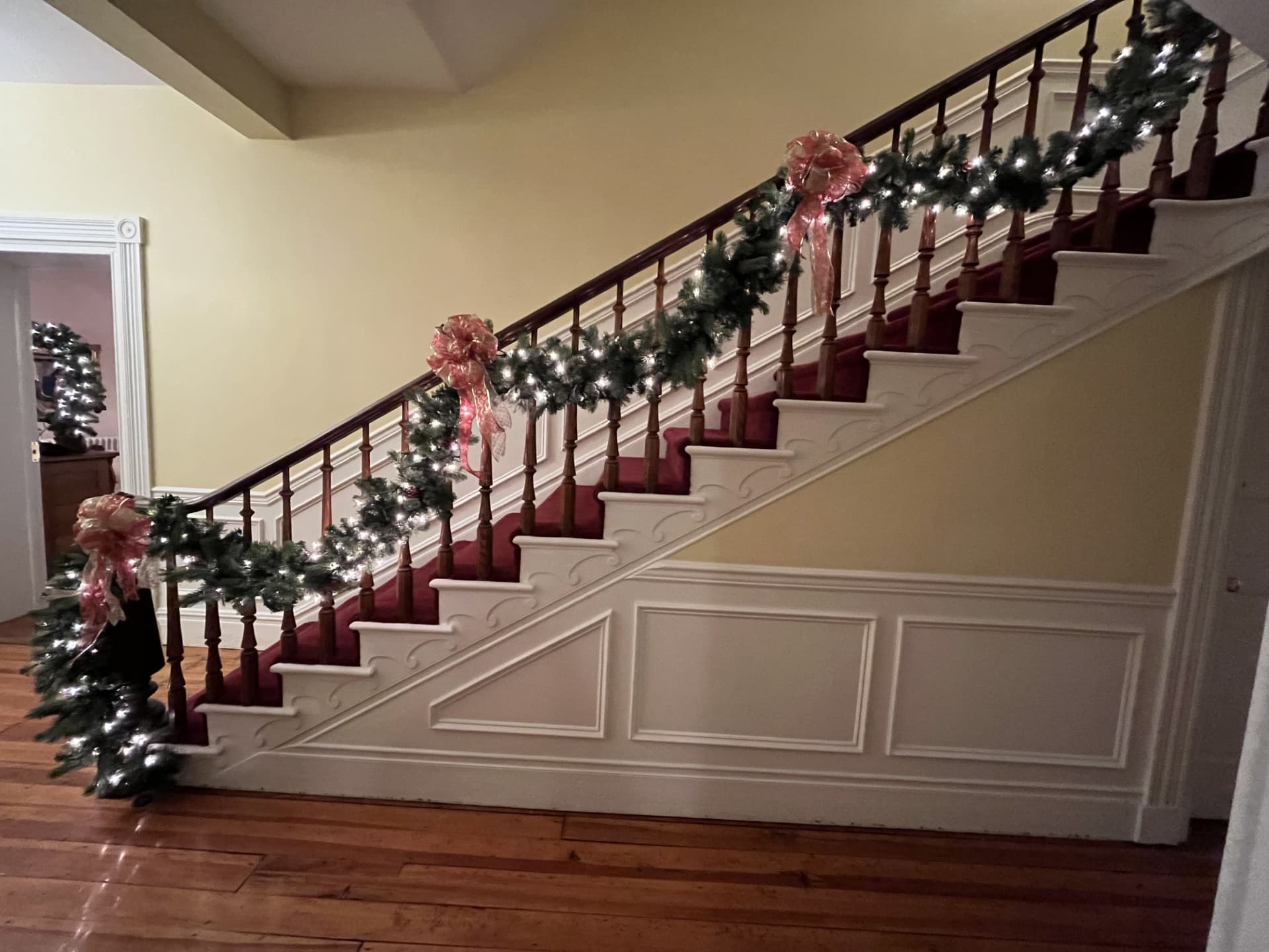 A festive staircase adorned with garlands, lights, and bows.