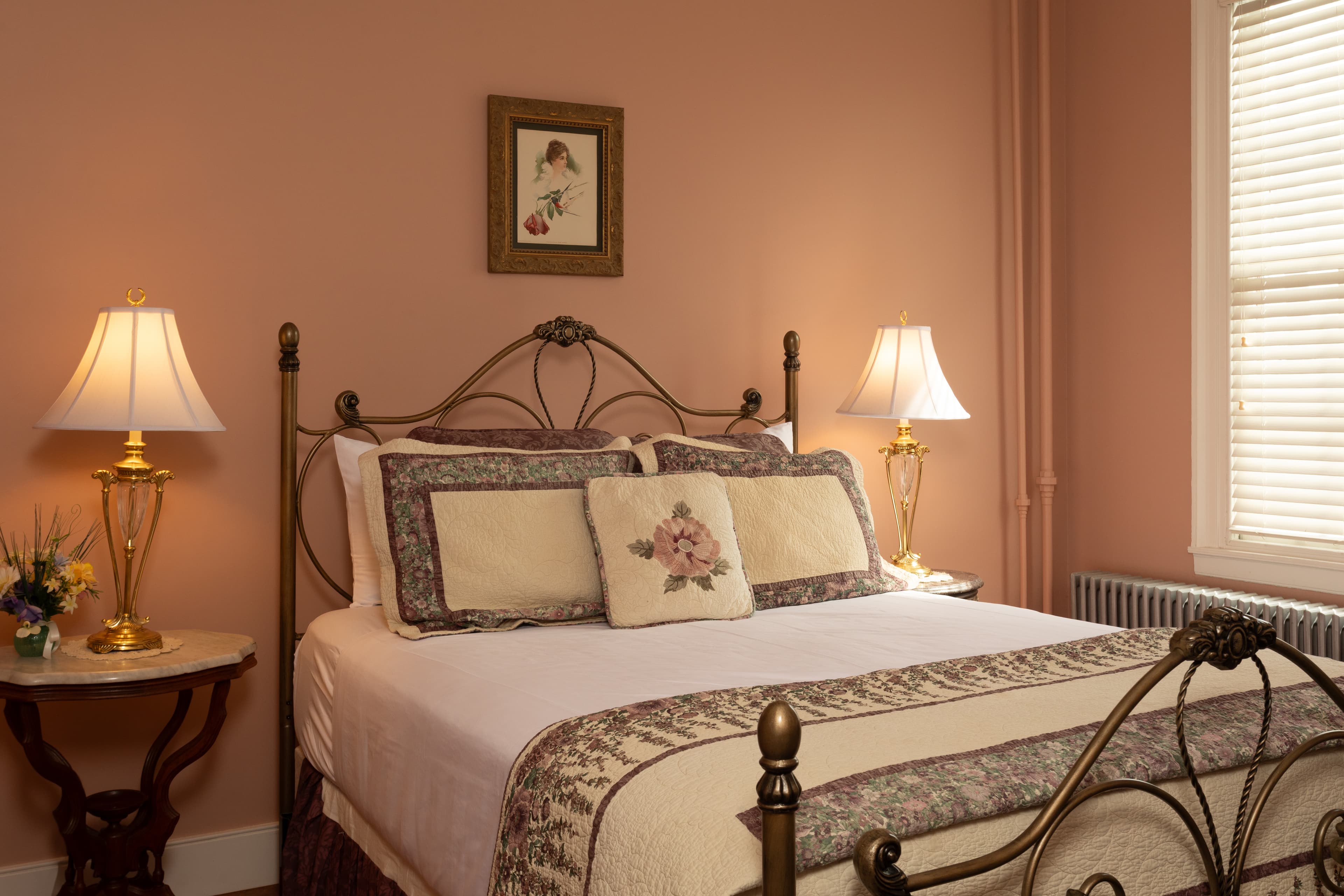 Cozy bedroom featuring a brass bed, floral bedding, and soft lighting.