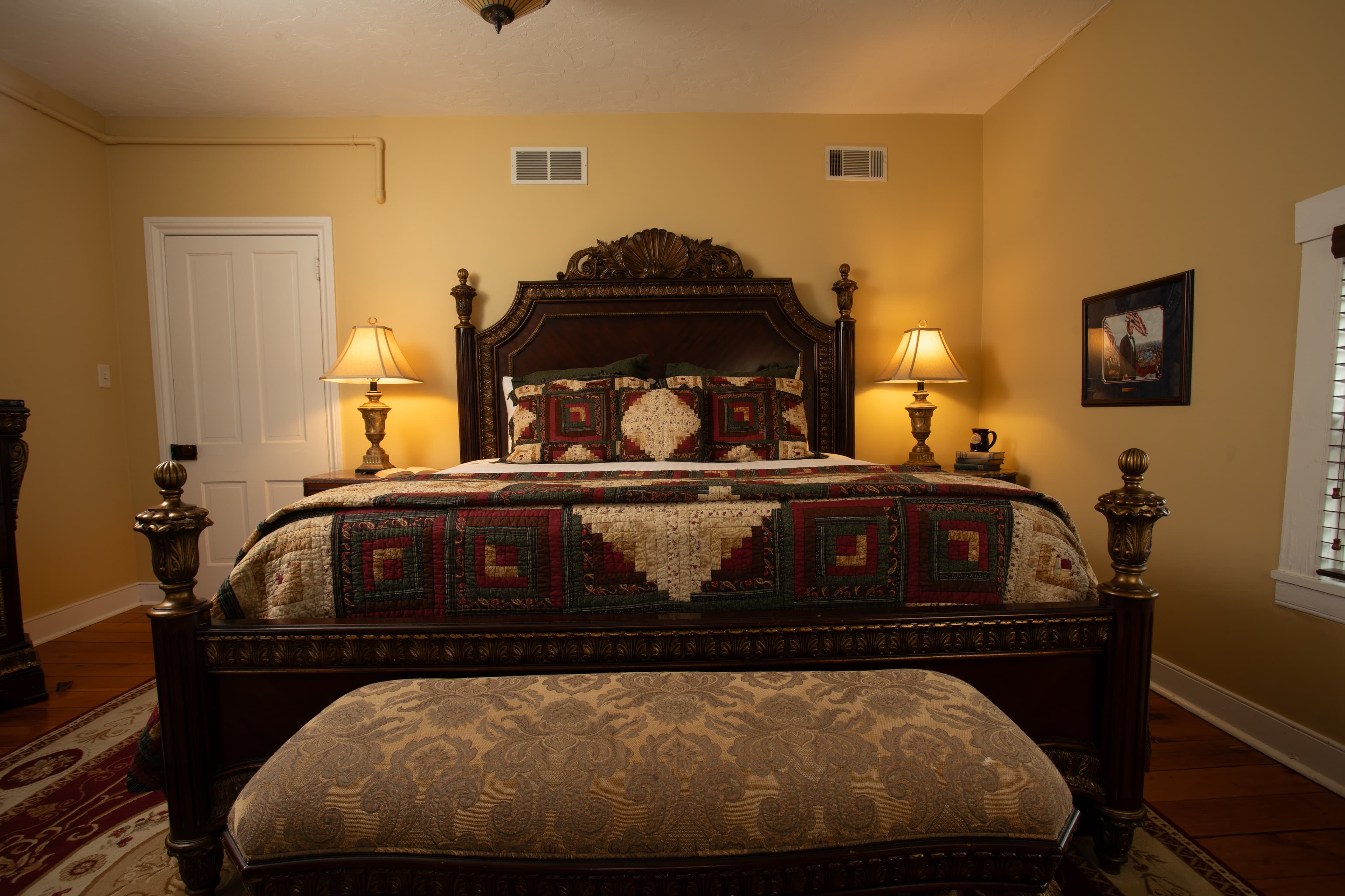 A cozy bedroom featuring a decorative bed, bedside lamps, and a patterned bench.