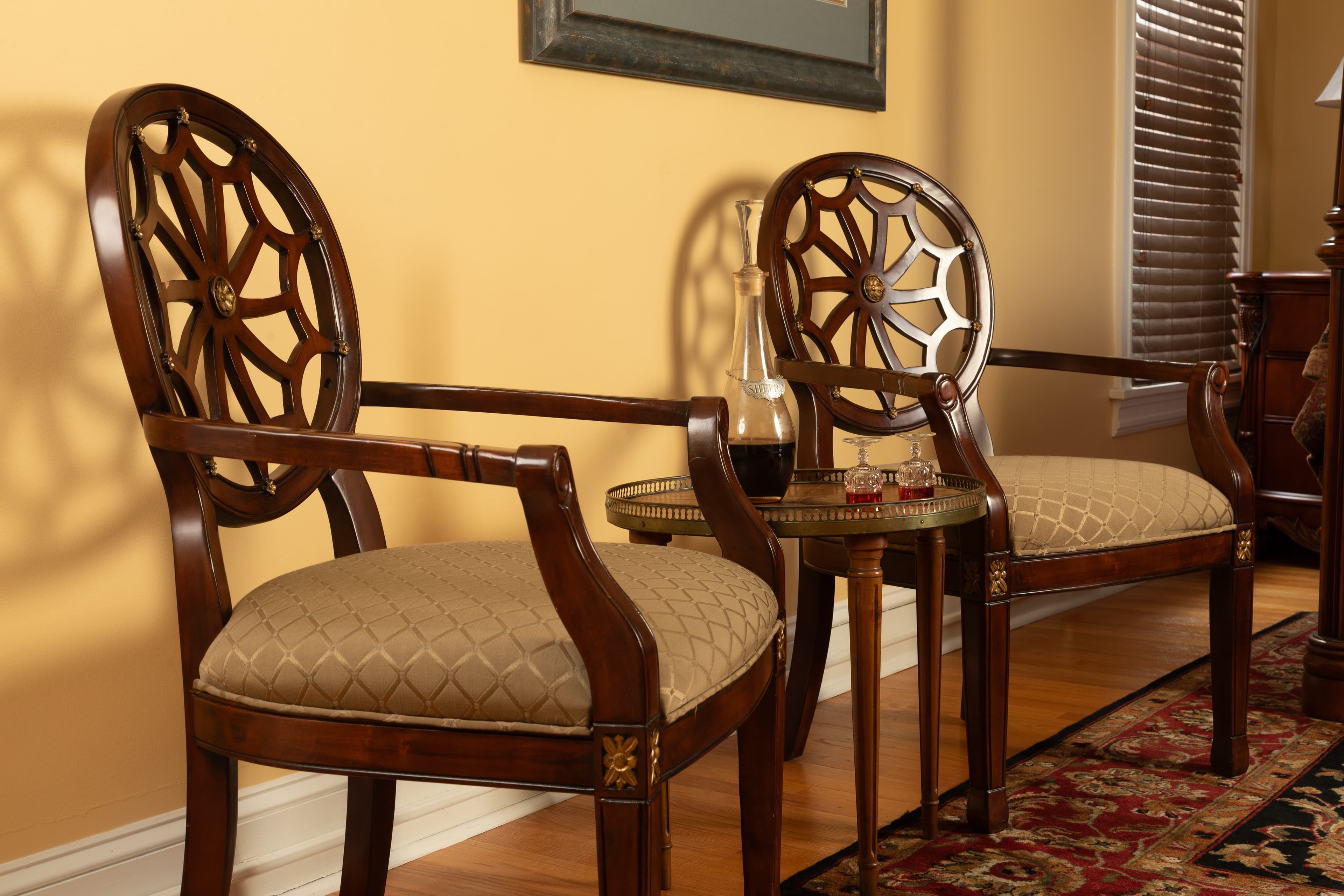 Two elegant wooden chairs with intricate backs and cushioned seats beside a small side table in a cozy room.