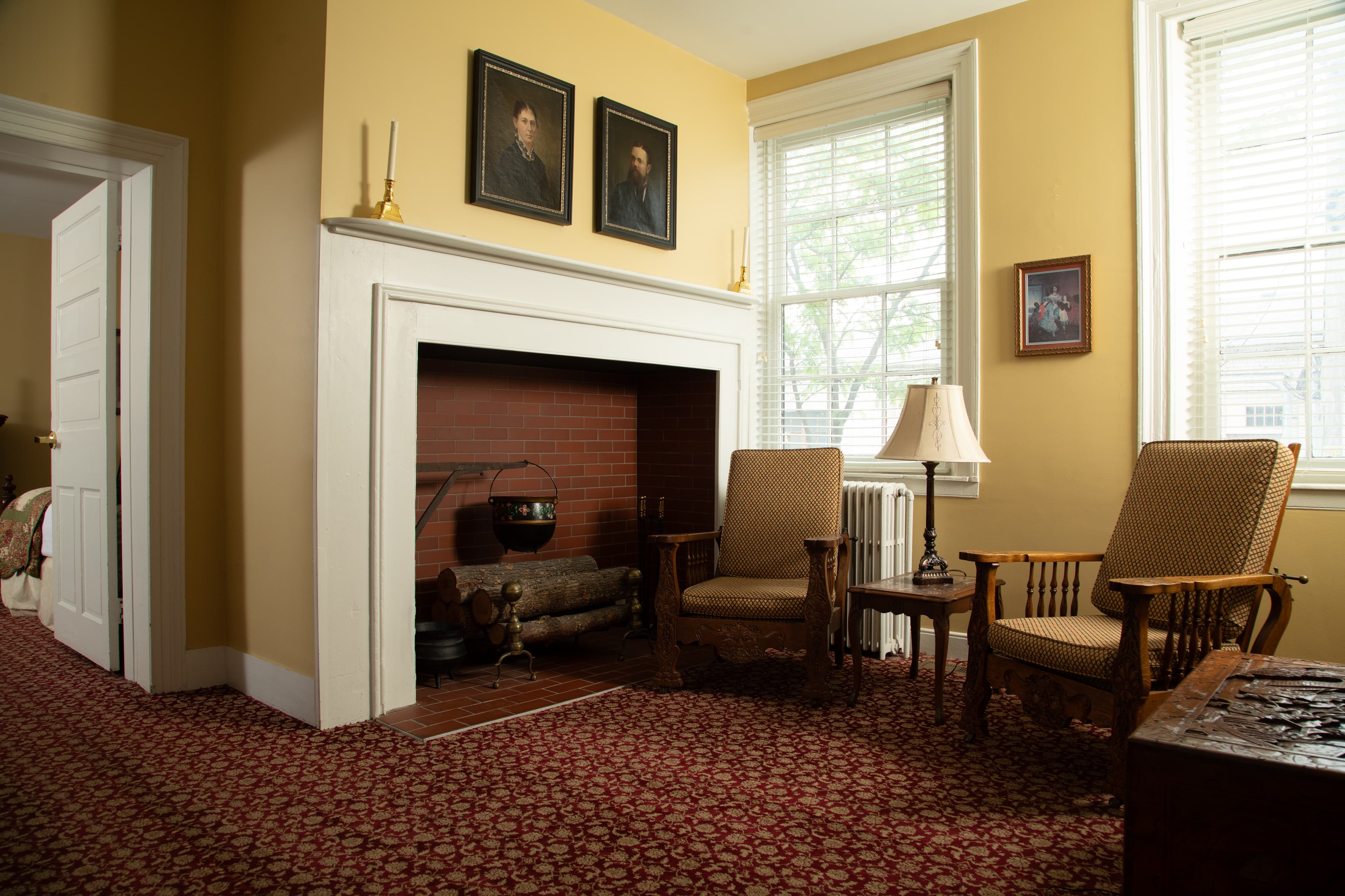 A cozy room featuring two chairs, a fireplace, and artwork on the walls.