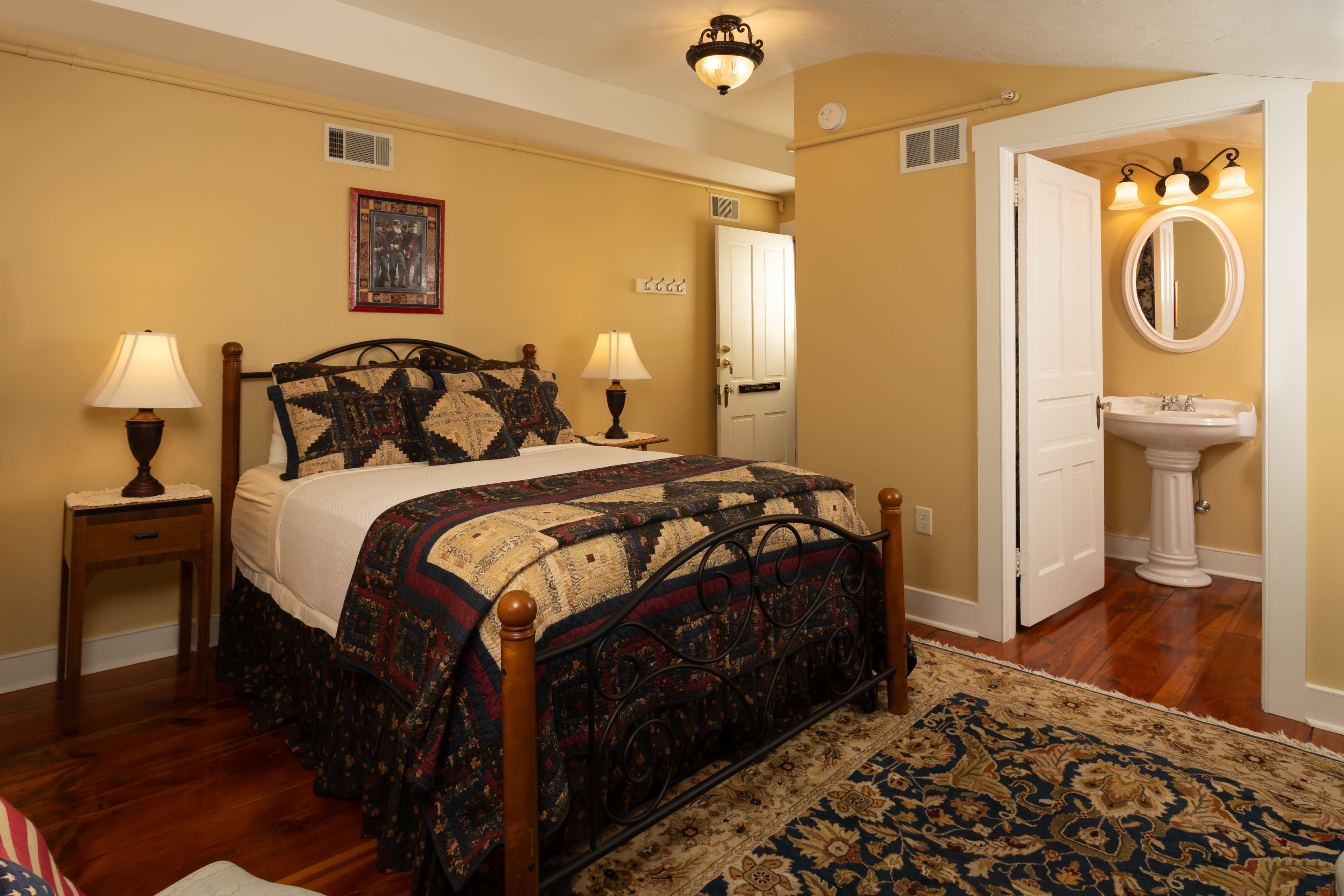 A cozy bedroom featuring a wooden bed, lamps, and an adjoining bathroom.