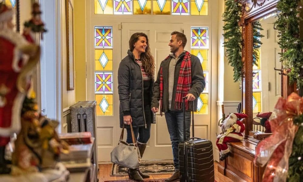 A couple arrives with luggage at Swope Manor entryway decorated for Christmas in Gettysburg.