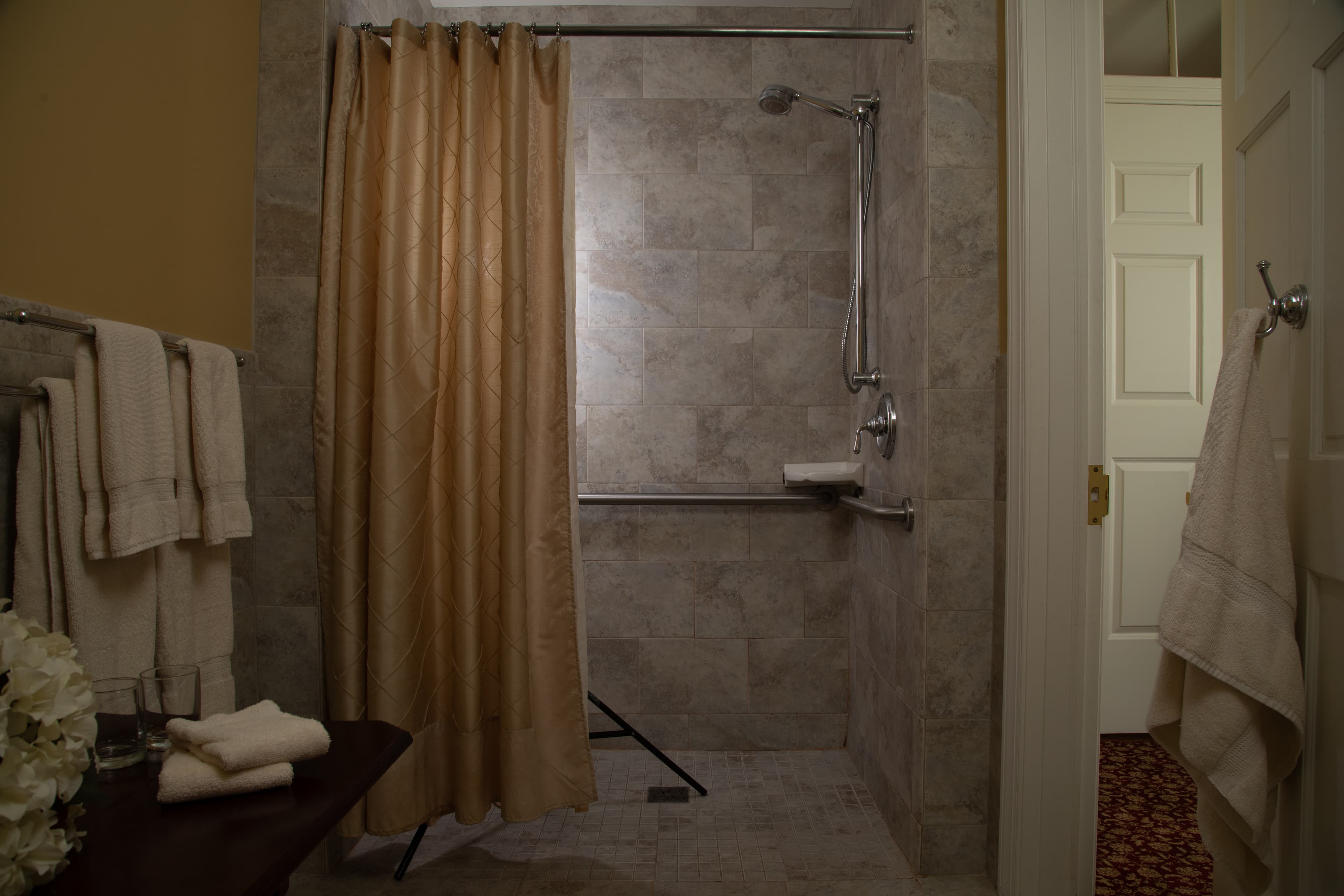 A spacious shower area with a beige curtain, tiled walls, and neatly arranged towels.